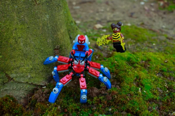 Cédric Manuel · 14/03/2026 · 2048 x 1365 Cette photographie met en scène deux figurines miniatures posées sur un tronc et de la mousse verte. Le sujet principal est un robot bleu et rouge en forme d'arachnide, accompagné d'une créature jaune et noire en arrière-plan.La composition est horizontale, avec un cadrage serré sur les figurines. La lumière naturelle, douce et légèrement tamisée, met en valeur les détails. Les couleurs dominantes sont les teintes vives des figurines (bleu, rouge, jaune, noir) contrastant avec le vert de la mousse.Le style évoque un univers ludique et fantastique, créant une ambiance miniature et onirique.