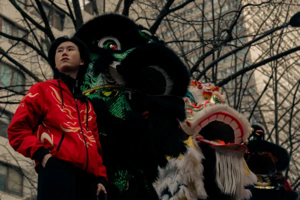 Don · 6601 x 4401 Cette photographie met en scène un homme en veste rouge posant devant deux masques traditionnels géants, probablement liés à une fête asiatique, comme le Nouvel An lunaire. La composition joue sur le contraste entre le sujet moderne et les éléments traditionnels. Le cadrage est serré, centré sur les visages des masques et l’homme.La lumière, tamisée, crée une ambiance dramatique et mystérieuse. Les couleurs dominantes sont les tons sombres des masques, contrastant avec le rouge vif de la veste. Le style est documentaire et artistique, évoquant une ambiance à la fois culturelle et contemplative.