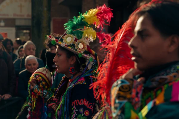Don · 6444 x 4296 Cette photographie capture deux personnes vêtues de costumes traditionnels colorés, probablement lors d’une fête culturelle. Le sujet principal est l’homme au premier plan, portant un chapeau orné de plumes rouges et jaunes et des accessoires brillants.La composition montre un cadrage serré, mettant en valeur les détails des costumes. La lumière est douce, avec des ombres marquées, créant une ambiance chaleureuse et festive. Les couleurs dominantes sont vives : rouge, jaune, vert et bleu, typiques des célébrations folkloriques. Le style est documentaire, capturant un moment authentique et dynamique, évoquant une ambiance joyeuse et traditionnelle.
