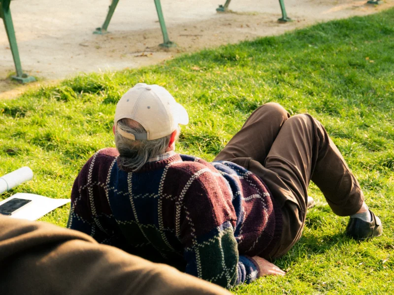 Seila · 21/03/2026 · 4379 x 3284 Cette photographie montre un homme allongé sur l'herbe, vêtu d’un pull à motifs et d’un bonnet blanc, avec un masque sur le visage. Le sujet principal est flou, suggérant un mouvement ou une intention artistique.La composition est naturelle, avec un cadrage serré sur le sujet. La lumière semble douce et naturelle, probablement en extérieur. Les couleurs dominantes sont les tons verts de l’herbe, les teintes terreuses de ses vêtements et les touches de rouge et bleu du pull.Le style est réaliste et spontané, évoquant une ambiance calme et introspective.