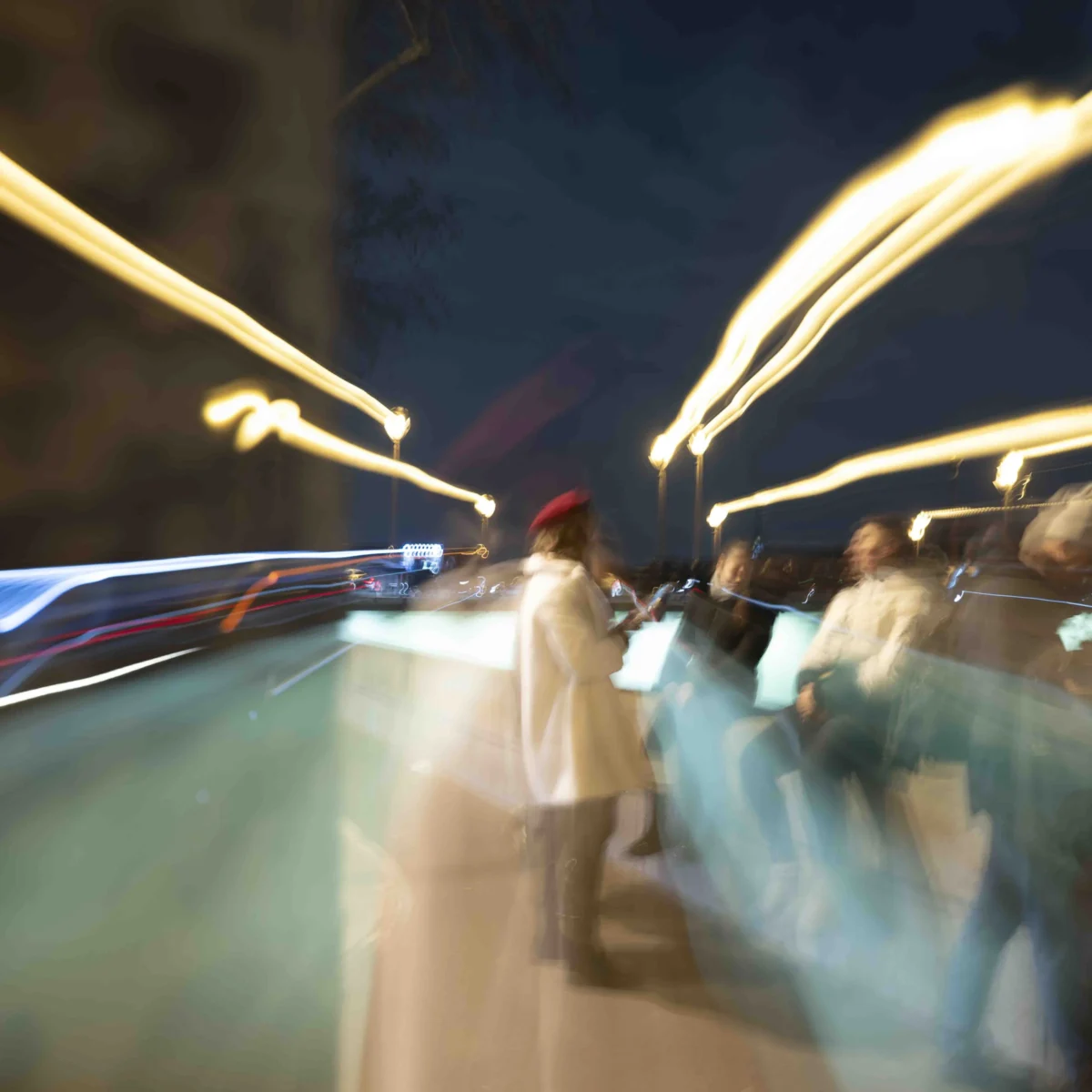 Jean-Paul · 19/12/2025 · 5355 x 5355 Cette photographie capture une scène nocturne floue et dynamique. Le **sujet principal** semble être un groupe de personnes en mouvement, suggéré par les silhouettes et les traînées lumineuses. La **composition** est désordonnée, avec des lignes de lumière qui traversent l’image, créant un effet de vitesse.Le **cadrage** est serré et légèrement décentré, accentuant le mouvement. La **lumière**, très présente, produit des traînées colorées (blanc, bleu, jaune), typiques d’une pose longue. Les **couleurs dominantes** sont des teintes froides et chaudes mélangées, donnant une ambiance **urbaine et énergique**.Le **style** est artistique et expérimental, évoquant une impression de vitesse et d’agitation. L’**ambiance** est nocturne, presque onirique, avec une touche de chaos contrôlé.
