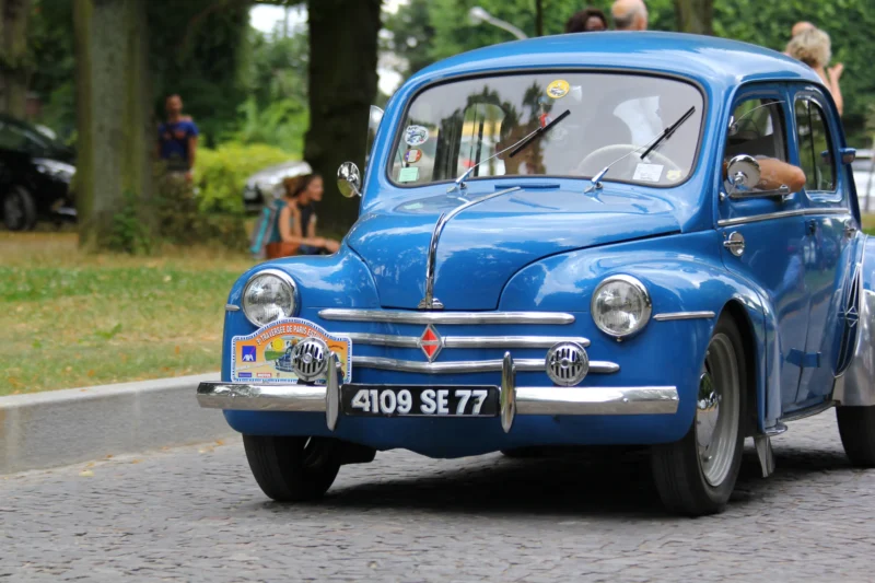 Frédéric · 31/07/2016 · 5184 x 3456 Cette photographie met en scène une vieille voiture Renault 4CV bleue comme sujet principal. La composition montre le véhicule en mouvement, légèrement de profil, avec un cadrage serré sur l'avant. La lumière naturelle, probablement en journée, éclaire bien la scène sans ombre marquée.Les couleurs dominantes sont le bleu vif de la voiture et le blanc des éléments métalliques. Le style rétro évoque les années 1950. L’ambiance est dynamique et nostalgique, renforcée par le cadre verdoyant et les spectateurs en arrière-plan.