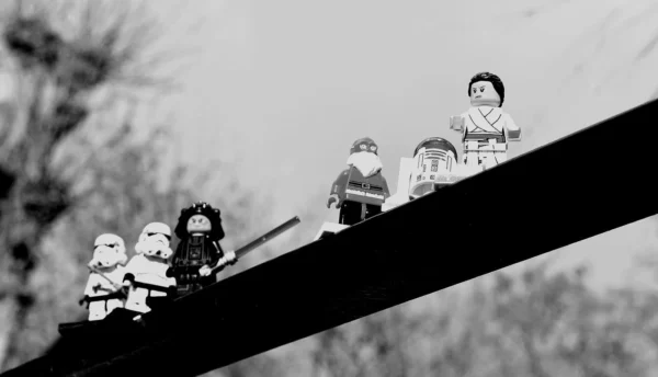 Franck TREBOIT · 14/03/2026 · 1400 x 802 Cette photographie en noir et blanc montre des figurines assises sur une branche, évoquant une scène de neige ou de montagne. Le sujet principal semble être ces personnages, dont certains portent des accessoires comme des bonnets et des bâtons.La composition est horizontale, avec un cadrage serré sur la branche. La lumière est douce, créant des contrastes subtils. L’ambiance est nostalgique et légèrement onirique, renforcée par le style rétro et le flou des contours. Les couleurs dominantes, bien que monochromes, suggèrent des tons froids et gris. L’ensemble dégage une impression de simplicité et de poésie.