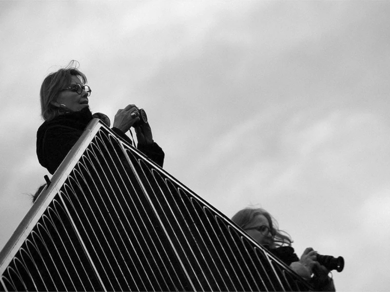 Photos in Paris Cette photographie en noir et blanc met en scène deux personnes sur un toit en pente, probablement des cheminées. Le sujet principal semble être l’une des silhouettes, partiellement visible, en train de s’accrocher ou de travailler.La composition est dynamique, avec un cadrage serré qui isole les sujets du reste de l’environnement. La lumière, diffuse et contrastée, accentue les formes et crée des ombres marquées, renforçant l’aspect dramatique. Les tons dominants, en niveaux de gris, soulignent les textures et les contours.Le style est documentaire et brut, évoquant une ambiance de travail ou d’effort, presque théâtrale.