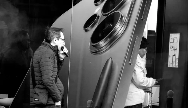 Franck TREBOIT · 02/03/2026 · 1400 x 804 Cette photographie en noir et blanc montre deux hommes dans un espace industriel ou technique. Le sujet principal semble être l’un d’eux, penché sur une machine complexe avec des éléments circulaires, probablement un appareil scientifique ou médical.La composition est dynamique, avec un cadrage serré sur les détails techniques. La lumière est contrastée, mettant en valeur les contours et les textures. L’ambiance est technique et professionnelle, renforcée par les ombres et les jeux de lumière.Le style est documentaire, réaliste, et dépourvu de couleurs, accentuant les contrastes et les formes géométriques.