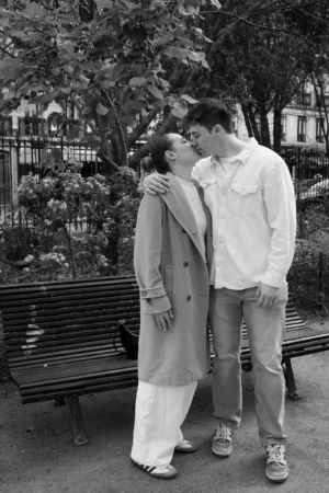 Claude · 3473 x 5209 Cette photographie en noir et blanc met en scène un couple en train de s'embrasser tendrement. Le sujet principal est leur complicité, capturée avec naturel.La composition montre un cadrage serré sur eux, avec un fond flou de banc et d'arbres. La lumière douce, probablement naturelle, éclaire leur visage, créant des contrastes subtils. L'absence de couleurs accentue les textures et les émotions.Le style est sobre et intime, évoquant une ambiance romantique et nostalgique, typique des clichés vintage. L'atmosphère est chaleureuse et poétique.
