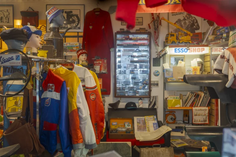 Thierry · 19/04/2026 · 3840 x 2560 Cette photographie montre un magasin de vêtements de travail et de protection, probablement spécialisé dans les tenues de sécurité ou professionnelles. Le sujet principal est un employé souriant, entouré de combinaisons colorées (bleue, rouge, blanche).La composition est serrée, avec un cadrage en plan moyen, mettant en valeur les vêtements et l’espace encombré. La lumière semble artificielle, éclairant les produits de manière uniforme. Les couleurs dominantes sont vives : rouge, bleu, jaune, et blanc.L’ambiance est chaleureuse et professionnelle, évoquant un commerce spécialisé et bien achalandé. Le style est réaliste et documentaire.