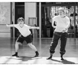 Thierry · 22/04/2026 · 3840 x 2560 Cette photographie en noir et blanc montre deux danseurs en train de s'étirer dans une salle de ballet. Le sujet principal est leur posture dynamique et élancée. La composition met en valeur leur symétrie et mouvement, encadrés par les barreaux et les miroirs en fond.Le cadrage est serré, capturant leurs corps en entier. La lumière est douce et uniforme, sans ombres marquées, créant une ambiance studieuse et artistique. Le style est épuré et classique, renforcé par le traitement monochrome. L'ambiance est à la fois intense et élégante, reflétant la discipline et la grâce du ballet.