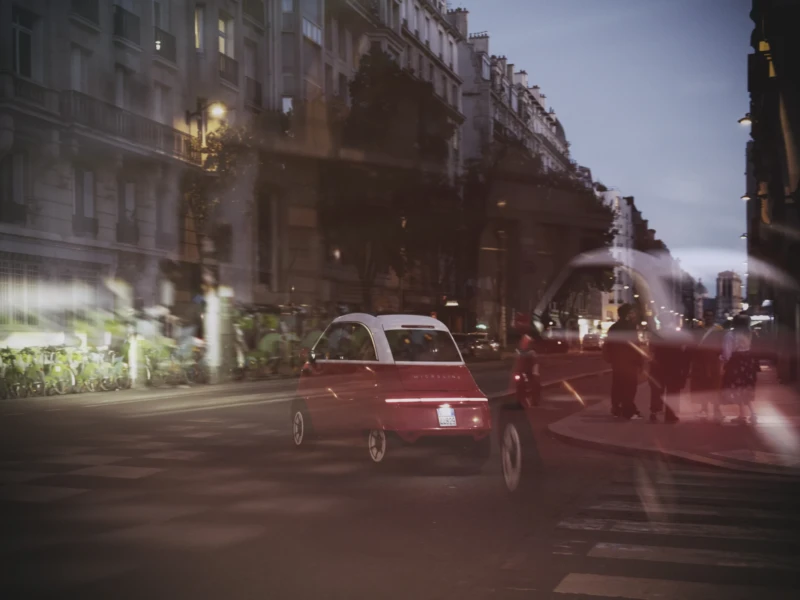 Thierry · 23/04/2026 · 3840 x 2560 Cette photographie capture une scène urbaine nocturne floue. Le sujet principal semble être une voiture rouge en mouvement, au premier plan. La composition met en valeur un jeu de lignes et de formes dynamiques, avec des éléments comme les bâtiments et les véhicules en arrière-plan légèrement floutés.Le cadrage est serré, centré sur la route. La lumière est tamisée, avec des teintes chaudes et des reflets de néons, créant une ambiance nocturne mystérieuse. Les couleurs dominantes sont des rouges, noirs et gris, renforçant l'atmosphère urbaine et moderne. Le style est cinétique, évoquant le mouvement et l'énergie de la ville.