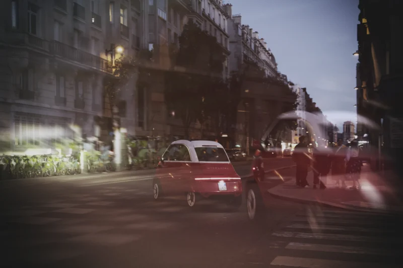 Thierry · 23/04/2026 · 3840 x 2560 Cette photographie capture une scène urbaine nocturne floue. Le sujet principal semble être une voiture rouge en mouvement, au premier plan. La composition met en valeur un jeu de lignes et de formes dynamiques, avec des éléments comme les bâtiments et les véhicules en arrière-plan légèrement floutés.Le cadrage est serré, centré sur la route. La lumière est tamisée, avec des teintes chaudes et des reflets de néons, créant une ambiance nocturne mystérieuse. Les couleurs dominantes sont des rouges, noirs et gris, renforçant l'atmosphère urbaine et moderne. Le style est cinétique, évoquant le mouvement et l'énergie de la ville.