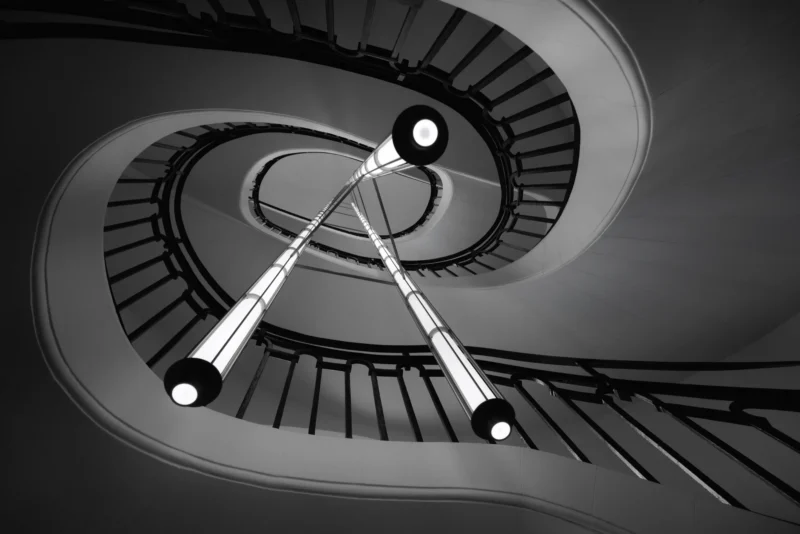 Philippe · 12/11/2025 · 3000 x 2001 Cette photographie met en scène un **escalier hélicoïdal** vu d’en haut, avec une **flèche** ou un objet pointu traversant les volées. La **composition** est dynamique, centrée sur la spirale et la ligne droite de l’objet, créant un jeu de perspectives.Le **cadrage** est serré, captant uniquement l’escalier et son centre. La **lumière**, contrastée, accentue les ombres et les formes géométriques. Les **couleurs dominantes** sont en noir et blanc, renforçant les contrastes et les textures.Le **style** est épuré et artistique, évoquant une **ambiance** mystérieuse et presque cinématographique.