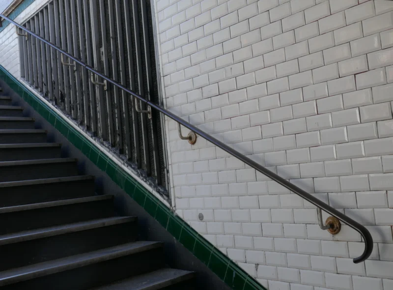 Bao · 3586 x 2646 Cette photographie montre principalement une rampe métallique verte fixée à un escalier en béton. La composition met en valeur les détails architecturaux, avec un cadrage serré sur la rampe et les marches. La lumière semble naturelle, bien que légèrement tamisée, créant des ombres douces.Les couleurs dominantes sont le vert métallique de la rampe, le gris clair des murs en briques, et le beige des marches. Le style est épuré et réaliste, évoquant une ambiance sobre et industrielle. L'ensemble dégage une impression de simplicité et de fonctionnalité.