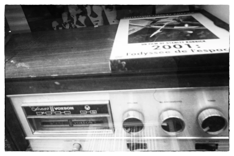 Thierry · 11/04/2026 · 3840 x 2560 Cette photographie en noir et blanc montre principalement un vieux magnétophone à cassettes, marqué "Grundig". En arrière-plan, on aperçoit un livre ou une brochure avec la mention "2001: Odyssey de l'espace".La composition est simple, avec un cadrage serré sur l'appareil, légèrement incliné. La lumière est douce, sans contraste marqué, créant une ambiance rétro et nostalgique. Les couleurs dominantes sont les tons de gris, typiques d'une photo en noir et blanc. Le style évoque une époque ancienne, renforçant une ambiance vintage et intemporelle.