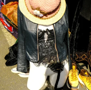 Nathalie F. · 25/04/2026 · 4160 x 4143 Cette photographie montre un mannequin vêtu d’une tenue originale. Le sujet principal est une personne portant un chapeau à large bord, une veste en cuir noir, un haut à motifs et des bottines blanches. Le cadrage est serré, centré sur le bas du corps.La lumière semble artificielle, mettant en valeur les détails. Les couleurs dominantes sont le noir, le blanc et des touches de couleurs vives (jaune des chaussures, motifs du haut). Le style est éclectique, mêlant élégance et excentricité. L’ambiance est théâtrale et avant-gardiste, évoquant une scène de mode ou un défilé.
