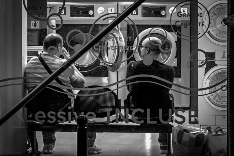 AnJo · 26/04/2026 · 4602 x 3068 Cette photographie en noir et blanc montre deux personnes, vêtues de combinaisons de protection, travaillant dans un espace industriel. Le sujet principal semble être leur activité autour d'appareils techniques, probablement des fours ou des machines de stérilisation.La composition est symétrique, avec une mise en scène centrée et des lignes diagonales formées par les barrières. Le cadrage est serré, mettant l'accent sur les détails des équipements et des combinaisons. La lumière est contrastée, créant des ombres marquées et accentuant les textures. L'ambiance est industrielle et technique, renforcée par le style documentaire et le flou partiel du texte "Exclusive Inclus".