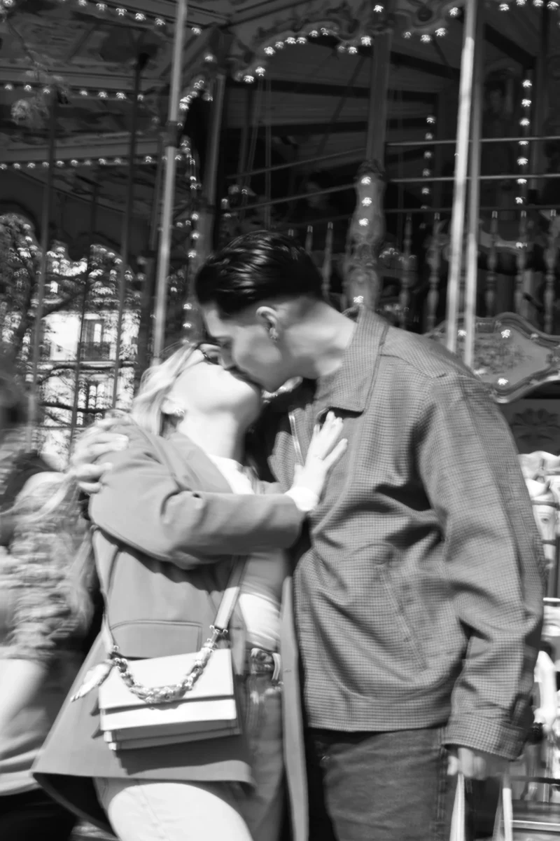 Aurélie · 15/01/2021 · 3712 x 5568 Cette photographie en noir et blanc montre deux personnes, probablement un couple, partageant un moment intime dans un carrousel. Le sujet principal est l’homme embrassant la nuque de la femme, assis sur un cheval de manège.La composition est serrée, centrée sur eux, avec un cadrage légèrement bas. La lumière est douce et tamisée, créant une ambiance nostalgique. Les couleurs dominantes sont les nuances de gris, typiques du noir et blanc.Le style évoque une époque ancienne, renforçant une ambiance romantique et mélancolique.
