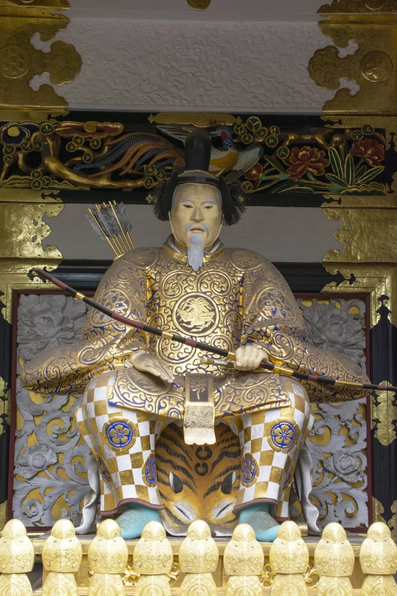 Dominique · 12/04/2024 · 1333 x 2000 Cette photographie représente une statue de guerrier japonais, probablement un daimyo ou un samouraï, en tenue traditionnelle richement ornée. Le sujet principal est centré, avec un cadrage serré mettant en valeur ses détails.La lumière, douce et légèrement dorée, accentue les textures des vêtements et crée des contrastes subtils. Les couleurs dominantes sont les tons dorés, noirs et blancs, typiques des tenues historiques japonaises.Le style est classique et traditionnel, évoquant un héritage culturel raffiné. L’ambiance est solennelle et majestueuse, renforcée par les éléments architecturaux élégants en arrière-plan.