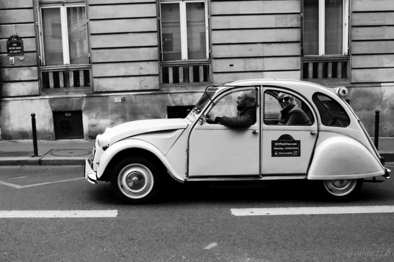 Cyrille · 11/04/2026 · 2026 x 1351 Cette photographie met en scène une **Citroën 2CV**, sujet principal emblématique. La composition est simple et épurée, avec un cadrage serré sur le véhicule, légèrement décentré vers la gauche. La lumière, naturelle et douce, crée des contrastes nets entre ombres et clartés, typiques d’un cliché en noir et blanc.Les couleurs dominantes sont les nuances de gris, renforçant l’aspect rétro et intemporel. Le style est documentaire et esthétique, évoquant une ambiance nostalgique et urbaine. L’image dégage une atmosphère paisible et charmante, mêlant simplicité et élégance.