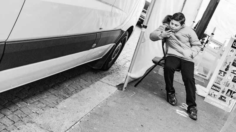 Muriel · 11/04/2026 · 2048 x 1152 Cette photographie montre un enfant, sujet principal, en train de se pencher pour toucher ou ajuster quelque chose près d'une voiture blanche. La composition est simple et naturelle, avec un cadrage serré sur le côté du véhicule et le bas du corps de l’enfant.La lumière est douce, probablement naturelle, créant des contrastes modérés. Les couleurs dominantes sont en noir et blanc, ce qui donne un style sobre et intemporel. L’ambiance est à la fois quotidienne et poétique, évoquant une scène spontanée et innocente.