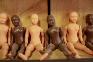 Cédric · 25/04/2026 · 2048 x 1365 Cette photographie montre une série de figurines en bois représentant des corps humains assis, disposés en rangée. Le sujet principal est ces figurines, dont certaines sont peintes en noir et d'autres laissées naturelles.La composition est linéaire et symétrique, avec un cadrage serré sur les figurines. La lumière est douce et uniforme, créant des ombres subtiles. Les couleurs dominantes sont le beige naturel du bois et le noir des figurines peintes.Le style est épuré et minimaliste, évoquant une ambiance à la fois artistique et légèrement mystérieuse.