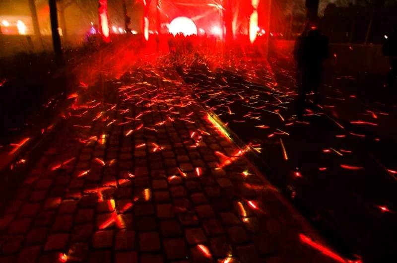 Pascale · 25/12/2025 · 1000 x 662 Cette photographie capture une allée pavée éclairée par une lumière rougeâtre et tamisée. Le sujet principal semble être l’effet des reflets et des ombres créés par les pavés et les éclats lumineux.La composition est symétrique et linéaire, avec une perspective convergente vers l’arrière-plan. Le cadrage est serré, mettant en valeur les détails des pavés et des éclats lumineux. Les couleurs dominantes sont le rouge et le noir, renforçant une ambiance mystérieuse et dramatique. Le style évoque une atmosphère cinématographique ou artistique, presque onirique.