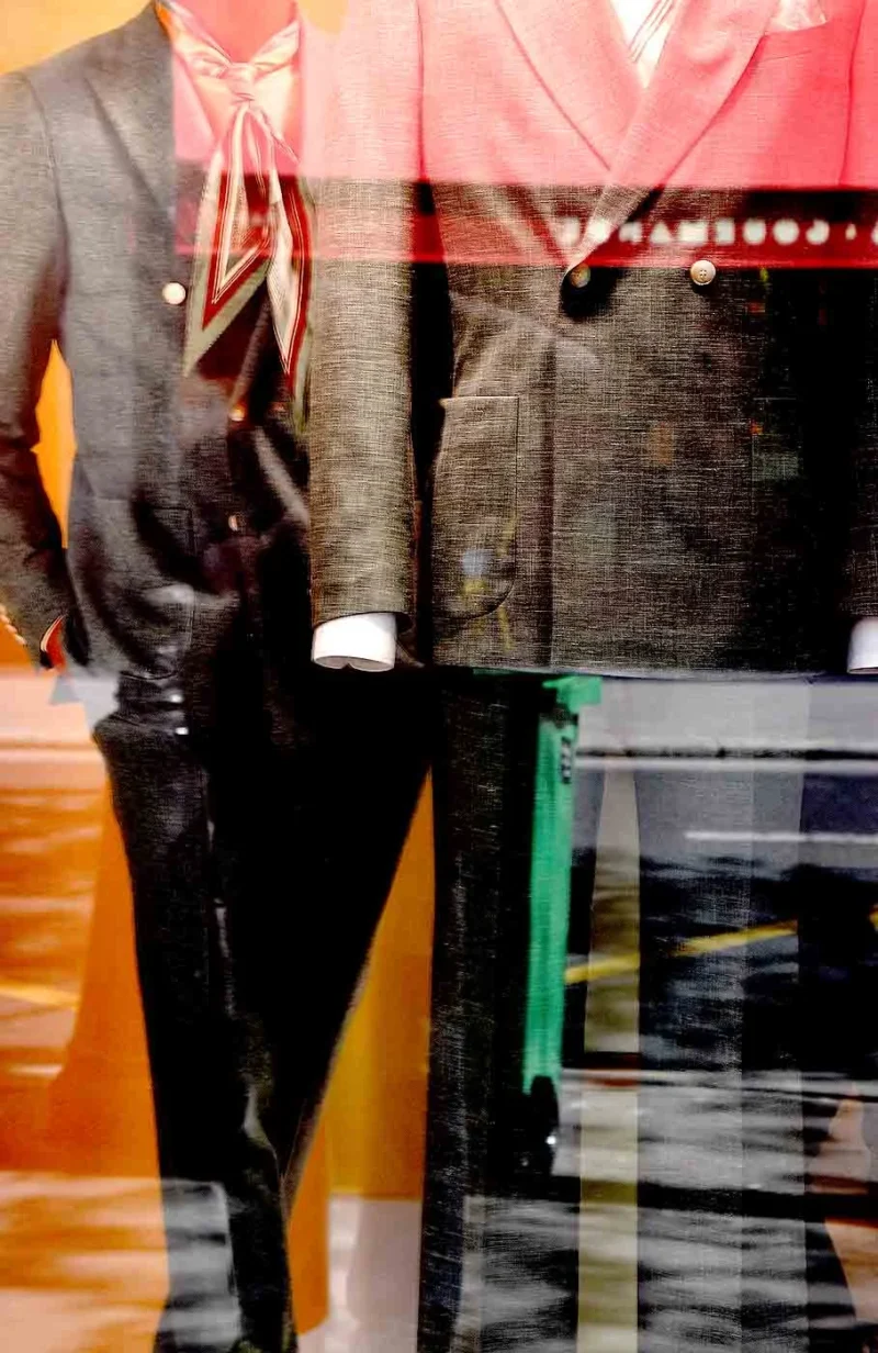 Franck T. · 25/04/2026 · 909 x 1400 Cette photographie met en scène un **sujet flou**, probablement une personne vêtue d’un costume, suggéré par les contours d’une veste et d’un pantalon.La **composition** est minimaliste, avec un **cadrage serré** sur les jambes et le bas du corps. Les **couleurs dominantes** sont des tons froids (gris, noir) contrastant avec des touches chaudes (orange, rouge) en arrière-plan.La **lumière** semble naturelle mais tamisée, créant une ambiance **sombre et mystérieuse**. Le style, proche du **flou artistique**, donne une impression de mouvement ou d’abstraction.L’**ambiance** est à la fois urbaine et onirique, évoquant une scène quotidienne transformée par un traitement esthétique.