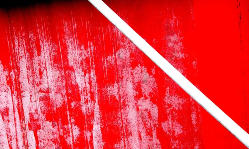 Franck T. · 08/12/2025 · 1400 x 842 Cette photographie met en scène une surface peinte en rouge vif, partiellement recouverte de blanc, formant une diagonale. Le sujet principal est cette opposition de couleurs et de textures, avec des traces de dégradation ou de peinture écaillée.Le cadrage est serré, centré sur ces éléments graphiques. La lumière semble naturelle et douce, mettant en valeur les contrastes et les irrégularités de la peinture. Les couleurs dominantes sont le rouge intense et le blanc pur, créant un style épuré et minimaliste. L’ambiance est à la fois industrielle et artistique, évoquant une esthétique brute et moderne.