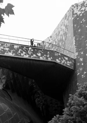 Pascale · 03/05/2026 · 1328 x 1876 Cette photographie en noir et blanc met en scène un **pont moderne** avec un motif géométrique en damier. Le **sujet principal** est une personne debout au centre du pont, offrant une impression de solitude et de perspective.La **composition** joue sur les lignes droites et la symétrie, renforcée par le cadrage serré. La **lumière**, douce et diffuse, crée des contrastes subtils entre ombres et clartés. Les **couleurs dominantes** sont les nuances de gris, accentuant l’aspect minimaliste et contemporain.Le **style** est épuré, presque abstrait, évoquant une **ambiance** à la fois froide et contemplative, mêlant urbanité et solitude.