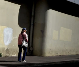Franck T. · 09/05/2026 · 1400 x 819 Cette photographie montre une personne comme sujet principal, vêtue d’une veste rouge et d’un jean, marchant sous un passage couvert. La composition est simple, avec un cadrage serré sur le sujet et un arrière-plan minimaliste.La lumière semble naturelle mais tamisée, créant des ombres douces. Les couleurs dominantes sont les tons neutres (gris, beige) du mur et du sol, rehaussés par la touche rouge de la veste. Le style est sobre et réaliste, évoquant une ambiance calme et introspective, presque mélancolique.