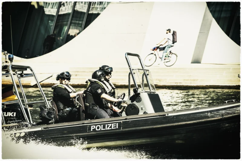 Thierry · 01/05/2026 · 3840 x 2560 Cette photographie capture un **sujet dynamique** : un **cycliste en l'air** exécutant un saut au-dessus d’un bateau de police. La **composition** oppose le mouvement du cycliste à la stabilité des policiers, créant un contraste saisissant. Le **cadrage** est serré sur le bateau et le sauteur, avec un arrière-plan flou.La **lumière** est douce, légèrement tamisée, donnant une ambiance **nostalgique**. Les **couleurs dominantes** sont des teintes sépia et grises, renforçant l’aspect vintage. Le **style** est documentaire et cinématographique, évoquant une scène **actionnée et intense**, avec une touche d’**aventure urbaine**.