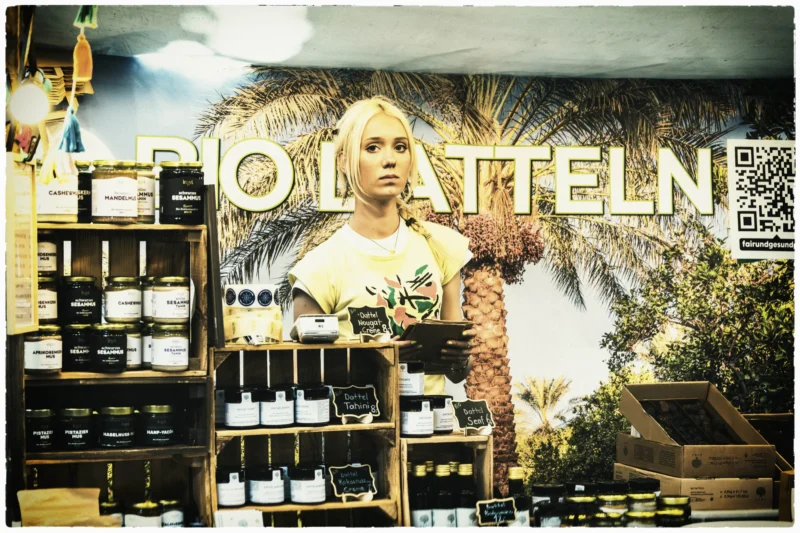 Thierry · 02/05/2026 · 3840 x 2560 Cette photographie montre une vitrine de magasin avec pour sujet principal une mannequin en robe jaune clair, stylisée et légèrement floue. La composition met en valeur des produits cosmétiques et de soins exposés sur des étagères à gauche.Le cadrage est serré, centré sur la vitrine. La lumière est douce et naturelle, avec des contrastes marqués. Les couleurs dominantes sont les tons chauds (jaune, beige) et des touches de vert et de blanc.Le style est moderne et épuré, évoquant une ambiance chic et élégante, typique d’un magasin haut de gamme.