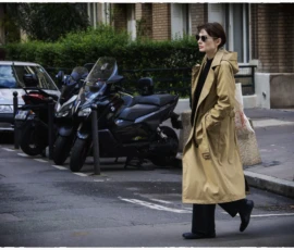 Thierry · 16/05/2026 · 3840 x 2560 Cette photographie met en scène une femme élégante comme sujet principal, vêtue d’un long trench beige et de bottes noires, marchant sur un trottoir. La composition montre une rue urbaine avec des scooters et voitures en arrière-plan.Le cadrage est serré sur elle, avec une profondeur de champ qui floute légèrement l’arrière-plan. La lumière est naturelle, tamisée, créant des ombres douces. Les couleurs dominantes sont les tons neutres (beige, gris) avec des touches de vert (végétation).Le style est sobre et contemporain, évoquant une ambiance calme et introspective, typique d’une ville européenne.