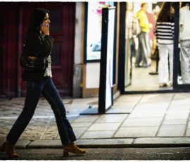 Thierry · 15/05/2026 · 3840 x 2560 Cette photographie met en scène une femme comme sujet principal, marchant de profil dans une rue urbaine. La composition est dynamique, avec un cadrage serré sur elle, isolée des autres passants en arrière-plan.La lumière, naturelle et tamisée, crée des contrastes doux et des ombres allongées. Les couleurs dominantes sont sobres : tons bleus foncés (vêtements), gris (trottoir) et teintes chaudes (souliers, éclairage urbain).Le style est réaliste et spontané, évoquant une ambiance urbaine nocturne ou crépusculaire, à la fois calme et légèrement mélancolique.