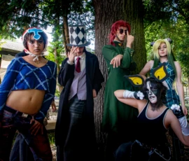 Taunia · 2200 x 1650 Cette photographie met en scène quatre personnes déguisées en personnages de style *anime* ou *cosplay*. Le sujet principal semble être ces cosplayers, posant devant un arbre.La composition est dynamique, avec un cadrage serré sur les personnages. La lumière naturelle, douce et légèrement tamisée, crée des ombres douces. Les couleurs dominantes sont vives : bleu, vert, noir et touches de rouge et jaune.Le style est festif et ludique, évoquant une ambiance convention ou festival de cosplay. L'atmosphère est joyeuse et créative, mettant en valeur les tenues élaborées et les expressions des personnages.