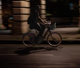 Claude · 5788 x 3859 Cette photographie capture un cycliste en mouvement, sujet principal flou suggérant une vitesse. La composition met en valeur le cycliste au centre, avec un cadrage serré qui isole la scène. La lumière est tamisée, ambiance nocturne ou crépusculaire, avec des teintes sombres et contrastées. Les couleurs dominantes sont les tons gris et noirs, renforçant l'atmosphère urbaine et mystérieuse. Le style est dynamique, presque cinétique, grâce au flou de mouvement. L'ambiance est à la fois moderne et intemporelle, évoquant une solitude urbaine dans la nuit.