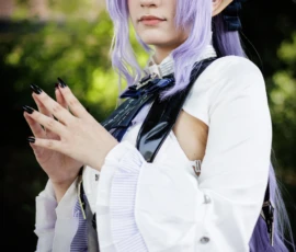 Claude · 3682 x 5523 Cette photographie met en scène un cosplayer vêtu d’un costume inspirant un personnage fantastique. Le sujet principal est une personne aux cheveux violets coiffés en pointe, portant une tenue blanche et noire avec des détails élégants et des accessoires comme des gants et une cape.Le cadrage est serré, centré sur le visage et le haut du corps. La lumière est douce et naturelle, éclairant le sujet de face avec une légère ombre sur la gauche. Les couleurs dominantes sont le violet des cheveux, le blanc de la tenue et les nuances grises et noires des accessoires.L’ambiance est à la fois mystérieuse et élégante, typique des conventions de cosplay.