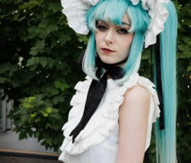 Claude · 3552 x 5627 Cette photographie met en scène une personne vêtue d’un costume cosplay. Le sujet principal porte une robe blanche élégante avec une large coiffe ornée de fleurs, des cheveux teints en bleu turquoise et une cravate noire. La composition est simple, avec un cadrage serré sur le haut du corps. La lumière naturelle, douce et légèrement tamisée, met en valeur les détails du costume. Les couleurs dominantes sont le blanc, le bleu turquoise et le noir, créant un contraste saisissant. Le style évoque une ambiance fantastique et théâtrale, typique des conventions de cosplay.