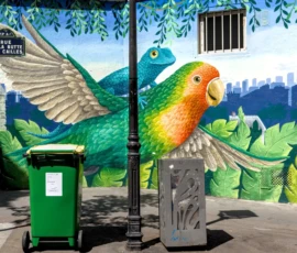 Thibault · 09/05/2026 · 1920 x 1371 Cette photographie met en scène un **mural coloré** comme sujet principal, représentant un **perroquet aux ailes déployées** dans un environnement végétal stylisé. La composition associe ce tableau mural à des éléments urbains (poubelles, boîte aux lettres).Le cadrage est serré, intégrant des détails architecturaux et naturels. La lumière semble naturelle, éclairant uniformément la scène. Les **couleurs dominantes** sont les verts, bleus et touches de gris, créant un contraste entre nature et ville.Le style est **artistique et réaliste**, mêlant précision et fantaisie. L’ambiance est à la fois **poétique et urbaine**, évoquant une harmonie entre nature et vie citadine.