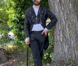 Thibault · 24/05/2026 · 1280 x 1920 Cette photographie montre un homme vêtu d’un costume élégant et vintage, incluant un haut-de-forme, une veste à motifs et un gilet. Il pose, canne à la main, devant un arbre dans un cadre naturel.Le cadrage est serré sur le sujet, avec un arrière-plan flou mettant en valeur sa silhouette. La lumière semble naturelle, douce et légèrement tamisée, créant des ombres douces. Les couleurs dominantes sont les tons sombres (noir, gris) du costume, contrastant avec le vert des feuilles et le marron de l’écorce.L’ambiance est à la fois mystérieuse et théâtrale, évoquant un style rétro ou steampunk.