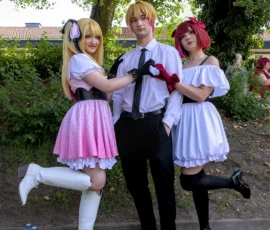 Thibault · 24/05/2026 · 1595 x 1920 Cette photographie met en scène trois personnes déguisées en personnages de style anime, probablement inspirés de *Ouran High School Host Club*. Le sujet principal est leur pose dynamique et souriante.La composition montre un cadrage serré sur les personnages, avec un arrière-plan flou de végétation et une maison. La lumière est naturelle, douce, et semble provenir d’un éclairage diurne. Les couleurs dominantes sont vives : rose, blanc, noir et rouge, renforçant l’ambiance ludique et festive. Le style est cosplay, typique des conventions manga/anime, créant une ambiance joyeuse et décontractée.