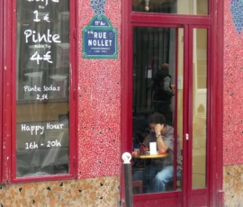 Marine · 16/05/2026 · 4000 x 3000 Cette photographie montre l’entrée d’un café nommé "La Nue Mollet". Le sujet principal est la porte rouge entrouverte, révélant une personne à l’intérieur. La composition met en valeur les enseignes indiquant les prix des pintes (4€) et des pintes étudiantes (2€), ainsi que l’heure du "Happy Hour" (16h-20h).Le cadrage est serré, centré sur la porte et les panneaux. La lumière est naturelle et douce, éclairant la façade. Les couleurs dominantes sont le rouge vif de la porte et le bleu des enseignes, créant un contraste chaleureux. L’ambiance est conviviale et typique d’un petit commerce urbain.