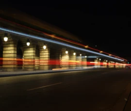 Francoise · 23/05/2026 · 6000 x 4000 Cette photographie capture une scène nocturne urbaine avec un **sujet principal** : les traînées lumineuses de véhicules en mouvement. La **composition** est horizontale, mettant en valeur une longue perspective de trottoir et de bâtiments. Le **cadrage** est serré sur la voie, créant un effet de profondeur.Les **lumières** dominent avec des teintes bleutées et rouges, typiques des phares et feux de voiture. Les **couleurs dominantes** sont sombres, avec des éclats lumineux vifs.Le **style** est dynamique, presque abstrait grâce aux traînées lumineuses. L’**ambiance** est nocturne et énergique, évoquant vitesse et mouvement dans une ville endormie.