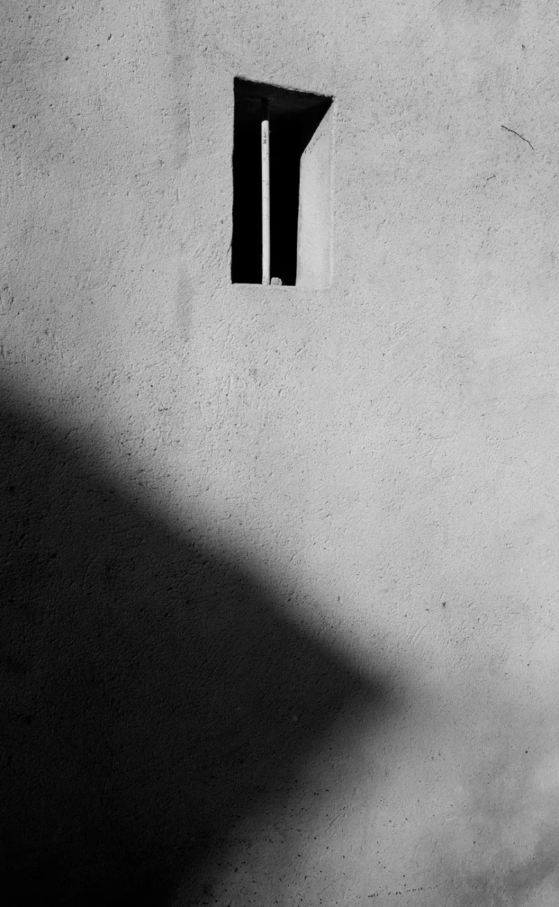 Franck T. · 15/05/2026 · 862 x 1400 Cette photographie met en scène un **sujet abstrait et minimaliste** : une lettre stylisée en forme de "T" encastrée dans un mur. La **composition** est épurée, centrée sur cet élément géométrique. Le **cadrage** est serré, isolant presque totalement le symbole.La **lumière**, naturelle et contrastée, crée des ombres marquées, accentuant la texture rugueuse du mur. Les **couleurs dominantes** sont en noir et blanc, renforçant le côté dramatique et monochrome. Le **style** est sobre et artistique, évoquant une ambiance **mystérieuse et contemplative**, presque industrielle.