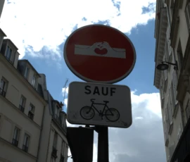 Bao · 6024 x 4016 Cette photographie montre un panneau de signalisation routier indiquant "SAUF" avec une exception pour les cyclistes. Le sujet principal est ce panneau, encadré entre des bâtiments en pierre.La composition est simple et centrée, avec un cadrage serré sur le panneau. La lumière naturelle, probablement en journée, éclaire la scène, créant des contrastes nets. Les couleurs dominantes sont les tons gris des bâtiments, le rouge du panneau et le blanc des inscriptions.Le style est documentaire et urbain, évoquant une ambiance de ville européenne, avec une touche de quotidienneté et de réglementation routière.