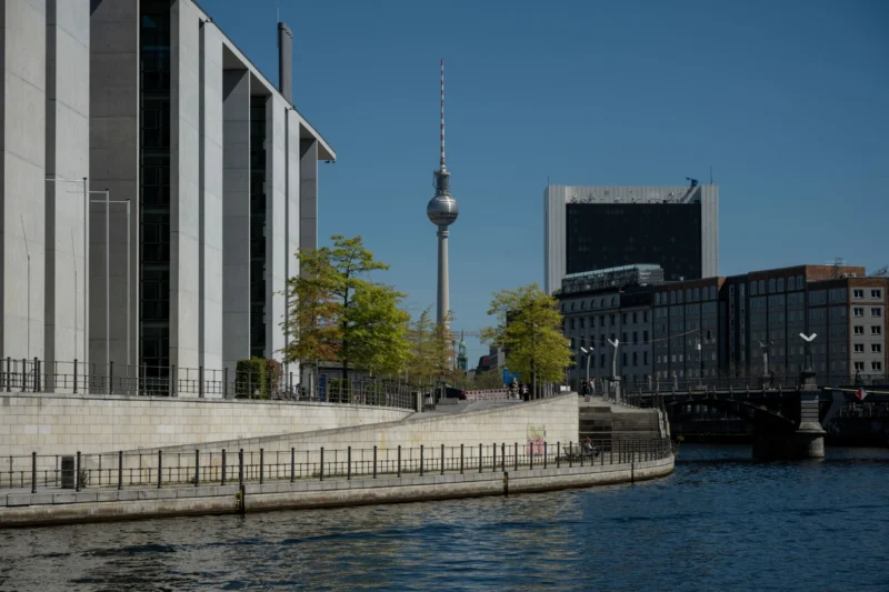 Jean-Marc · 01/05/2026 · 6048 x 4032 Cette photographie montre le **Fernsehturm de Berlin**, tour emblématique, comme sujet principal. La composition met en valeur le contraste entre l’architecture moderne et le cadre urbain. Le cadrage inclut une partie du canal et des bâtiments environnants, créant une perspective équilibrée.La lumière est vive et naturelle, typique d’un jour ensoleillé. Les couleurs dominantes sont les **tons gris des bâtiments**, le **bleu du ciel** et le **vert des arbres**. Le style est réaliste et documentaire, capturant une ambiance **calme et urbaine**, avec une touche de sérénité grâce à l’eau et l’architecture harmonieuse.