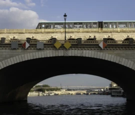 Alice · 07/05/2026 · 3923 x 2615 Cette photographie met en scène un **train traversant un pont en arc**. Le **sujet principal** est le train, encadré par l’architecture du pont en pierre.La **composition** est dynamique, avec une perspective basse soulignant l’arche. Le **cadrage** est serré sur le pont et le train, excluant les éléments superflus.La **lumière** est naturelle, probablement en journée, avec des contrastes modérés. Les **couleurs dominantes** sont les gris (pont, train), bleutées (eau, ciel) et quelques touches de jaune (panneaux).Le **style** est documentaire et réaliste, évoquant une **ambiance urbaine et industrielle**, mêlant mouvement et immobilité.