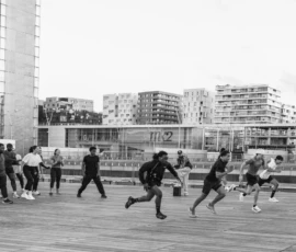 Alice · 07/05/2026 · 5189 x 3459 Cette photographie capture un groupe de personnes en mouvement, probablement en train de courir ou de marcher rapidement. Le sujet principal est l’énergie collective et dynamique des individus.La composition montre une scène urbaine avec un cadrage large incluant des bâtiments modernes en arrière-plan. La lumière est naturelle, probablement en journée, avec des contrastes nets créant des ombres marquées. En noir et blanc, les couleurs dominantes sont absentes, mais les tons varient du clair au foncé.Le style est documentaire et spontané, évoquant une ambiance de vie quotidienne et d’activité urbaine. L’atmosphère est dynamique et vivante.