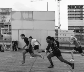 Alice · 07/05/2026 · 4132 x 2755 Cette photographie capture un groupe de jeunes en mouvement dynamique, probablement en train de jouer au football. Le sujet principal est l'action collective, avec des joueurs en action, certains en course.La composition est horizontale, avec un cadrage serré sur les joueurs, mettant en valeur leur énergie. L'arrière-plan, flou, montre un environnement urbain avec des bâtiments et des grues.La lumière est naturelle, probablement en journée, créant des contrastes nets. En noir et blanc, les couleurs dominantes sont absentes, mais les tons clairs et sombres renforcent les contrastes et les textures.Le style est documentaire et spontané, capturant un moment authentique. L'ambiance est vivante et énergique.