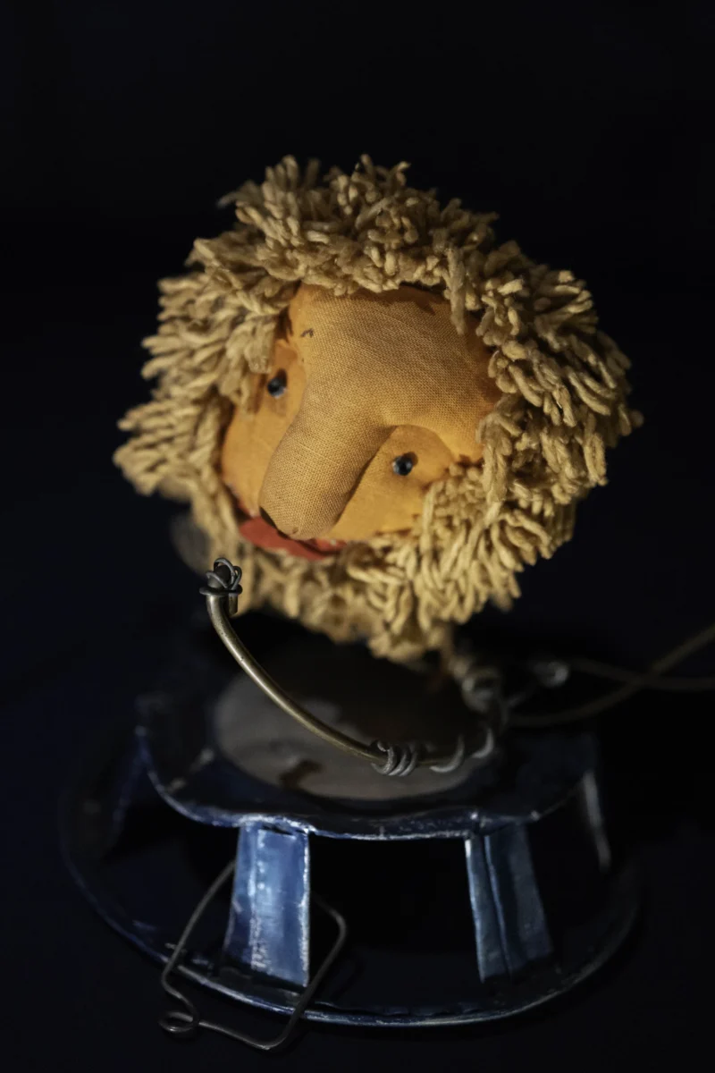 Alice · 23/05/2026 · 3575 x 5362 Cette photographie met en scène un objet étrange ressemblant à une tête humaine recouverte de fibres végétales sèches, probablement du blé ou du foin. Le cadrage est serré, centré sur le sujet posé sur un socle transparent.L’éclairage est tamisé, créant des ombres douces et une ambiance mystérieuse. Les couleurs dominantes sont des tons beiges et dorés pour la tête, contrastant avec le noir de l’arrière-plan. Le style évoque une touche surréaliste ou macabre, renforcée par l’aspect organique et déformé du sujet. L’ambiance est à la fois inquiétante et artistique.