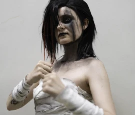 Alice · 24/05/2026 · 4605 x 5756 Cette photographie met en scène une personne en costume, probablement un personnage de fiction ou un cosplay. Le sujet principal, une femme aux traits marqués et maquillage sombre, semble blessée avec des bandages et du sang simulé.La composition est centrée, avec un cadrage serré sur le buste. La lumière est douce et uniforme, sans ombres marquées, créant un éclairage plat. Les couleurs dominantes sont les tons froids (blanc des bandages, noir du maquillage) et des touches de rouge sang.Le style est réaliste et dramatique, évoquant une ambiance sombre et intense, presque théâtrale.